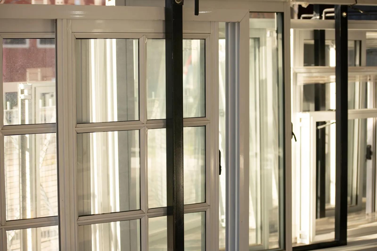 Close-up of white window frames with divided-light grille panes backlit by sunlight